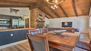 A spacious dining area with a large wooden table and comfortable seating, a kitchen with modern appliances, and a cozy fireplace.
