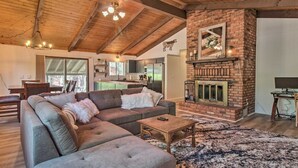 A cozy living room with a sectional sofa, a fireplace, and a dining area with a kitchen in the background.