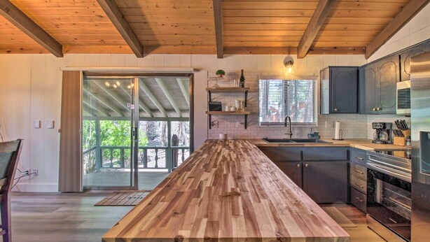 A modern kitchen with a wooden island, stainless steel appliances, and a sliding glass door leading to a balcony.