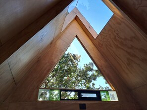 A triangular skylight with a view of trees and a clear sky. - Ko Glamping (Valdivia)