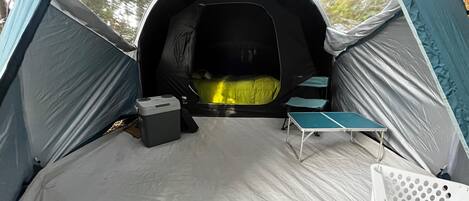 Una carpa con zona de descanso, una mesa y una pequeña silla.