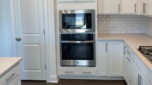 A modern kitchen with white cabinetry, stainless steel appliances, and a tiled backsplash. - 4BR Knightdale Home • Fast Wi-Fi • Near Downtown Raleigh (Knightdale)