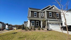 A two-story house with a garage, a well-maintained lawn, and a clear blue sky. - 4BR Knightdale Home • Fast Wi-Fi • Near Downtown Raleigh (Knightdale)