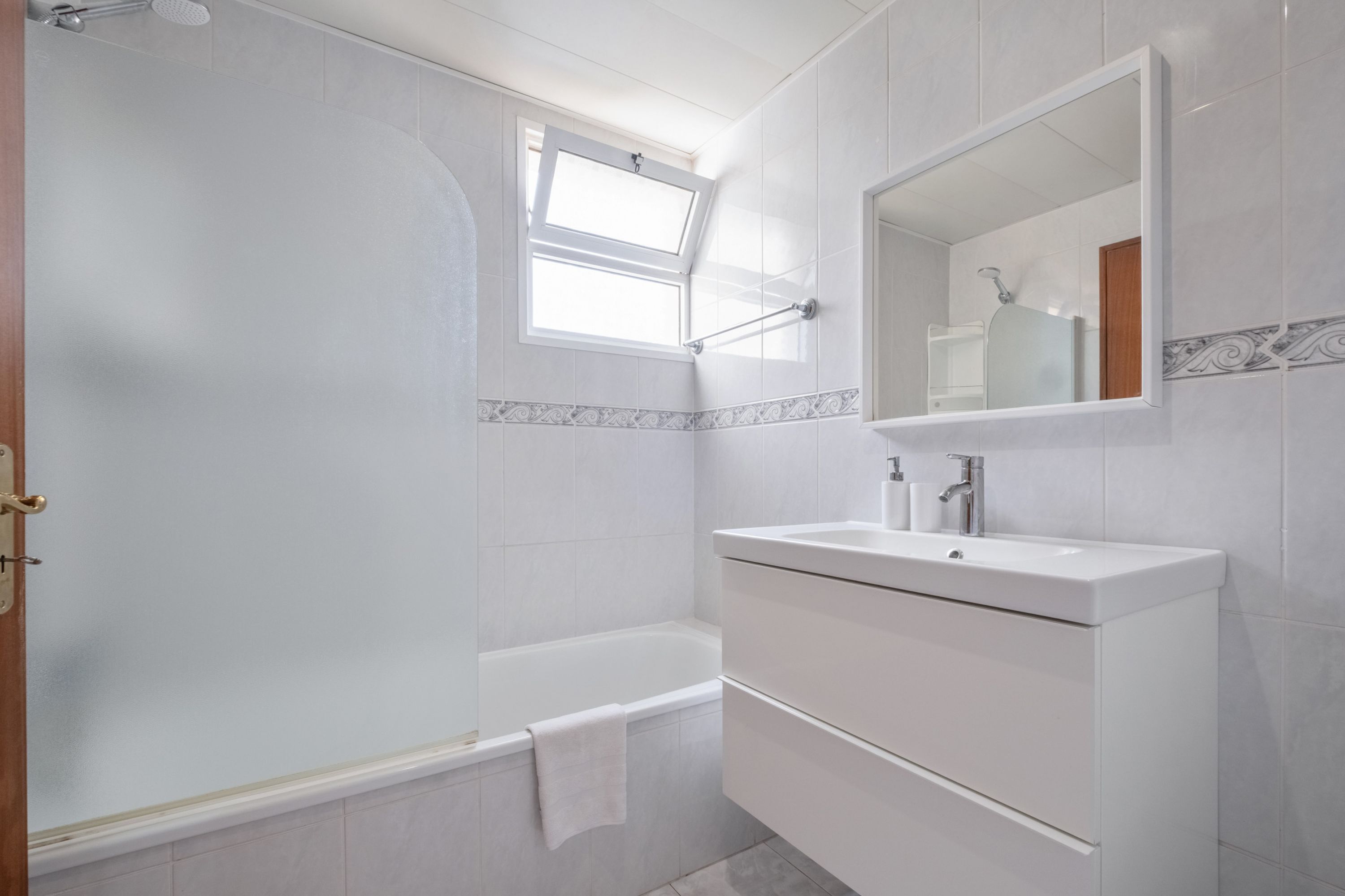 A modern bathroom with a bathtub, a vanity with a mirror, and a window.