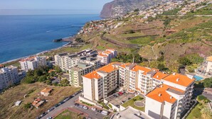 Un área residencial costera con edificios de apartamentos, una carretera y vistas al mar y las colinas.