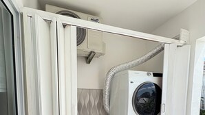 Ein kleiner Hauswirtschaftsraum mit Waschmaschine und Trockner, einem Waschbecken und einer Klimaanlage.