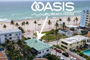 Una casa de playa llamada OASIS con vista al océano, palmeras y un camino que lleva a la playa.