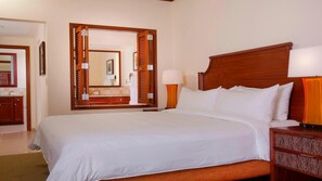 A hotel room with a large bed, a wooden headboard, a nightstand with a lamp, and a mirror above the bed. - Spacious Family Suite, Stunning Mountain View-1 Bd. Marriott's Ko Olina Beach (Kapolei)