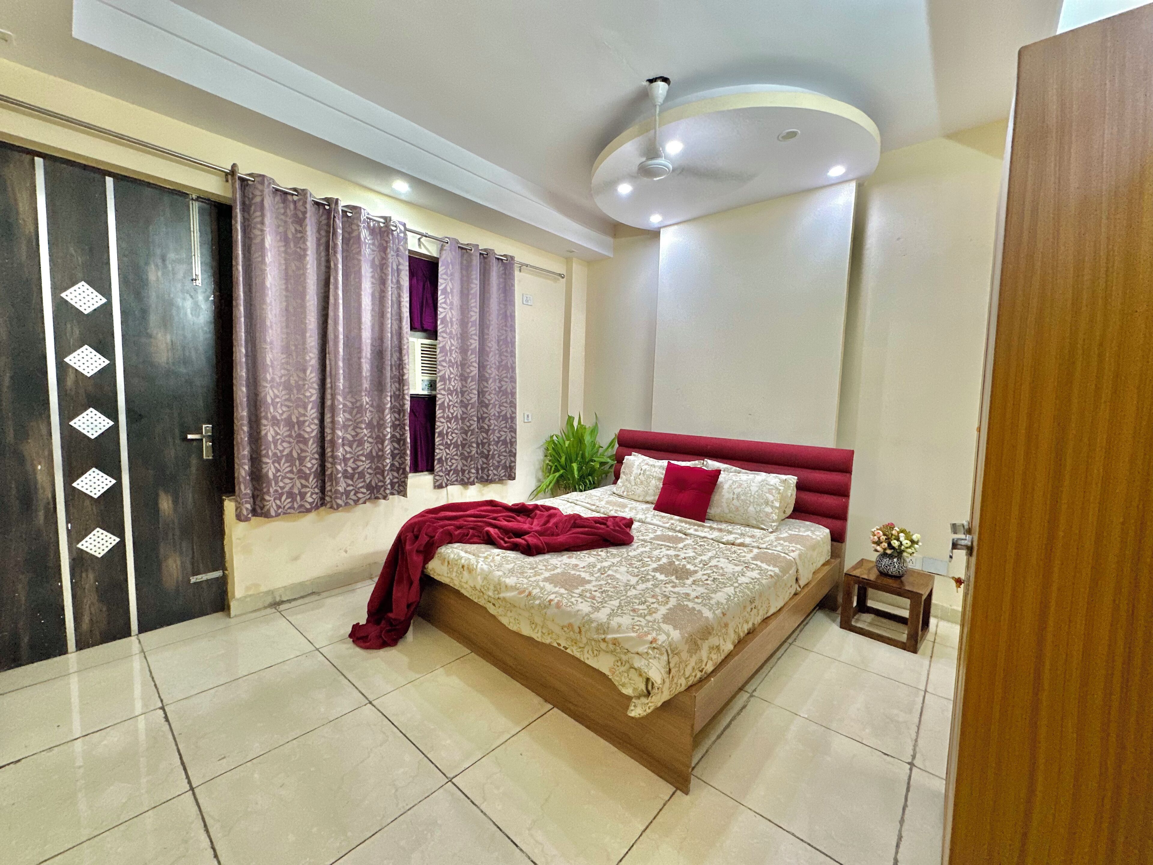 A bedroom with a bed, a nightstand, a potted plant, and a ceiling fan.