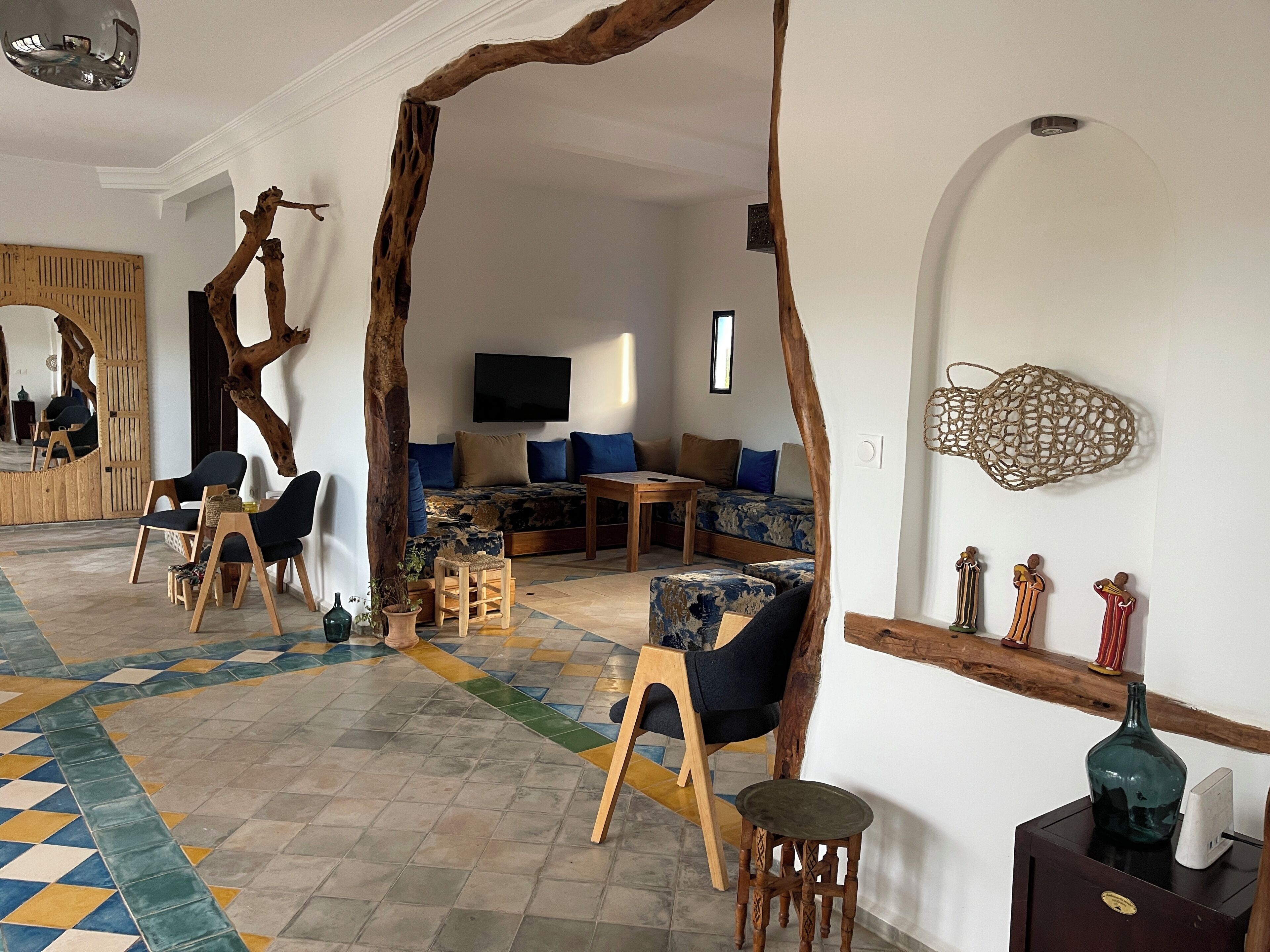 Una sala de estar moderna con un espejo grande, muebles de madera, piso estampado y un televisor de pantalla plana.