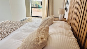 A hotel room with a bed, a patterned area rug, a window with curtains, and a lamp on a nightstand. - LaPerleD'argan (Essaouira)