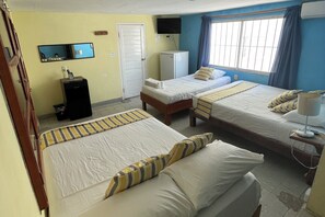 Une chambre d’hôtel avec deux lits, un bureau, une télévision et une fenêtre avec des rideaux.