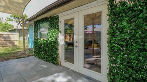 Une maison dotée d’un patio couvert, d’une porte-fenêtre coulissante et d’un mur recouvert de lierre.