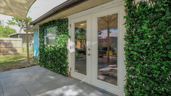 A house with a covered patio, a sliding glass door, and a wall covered in ivy.