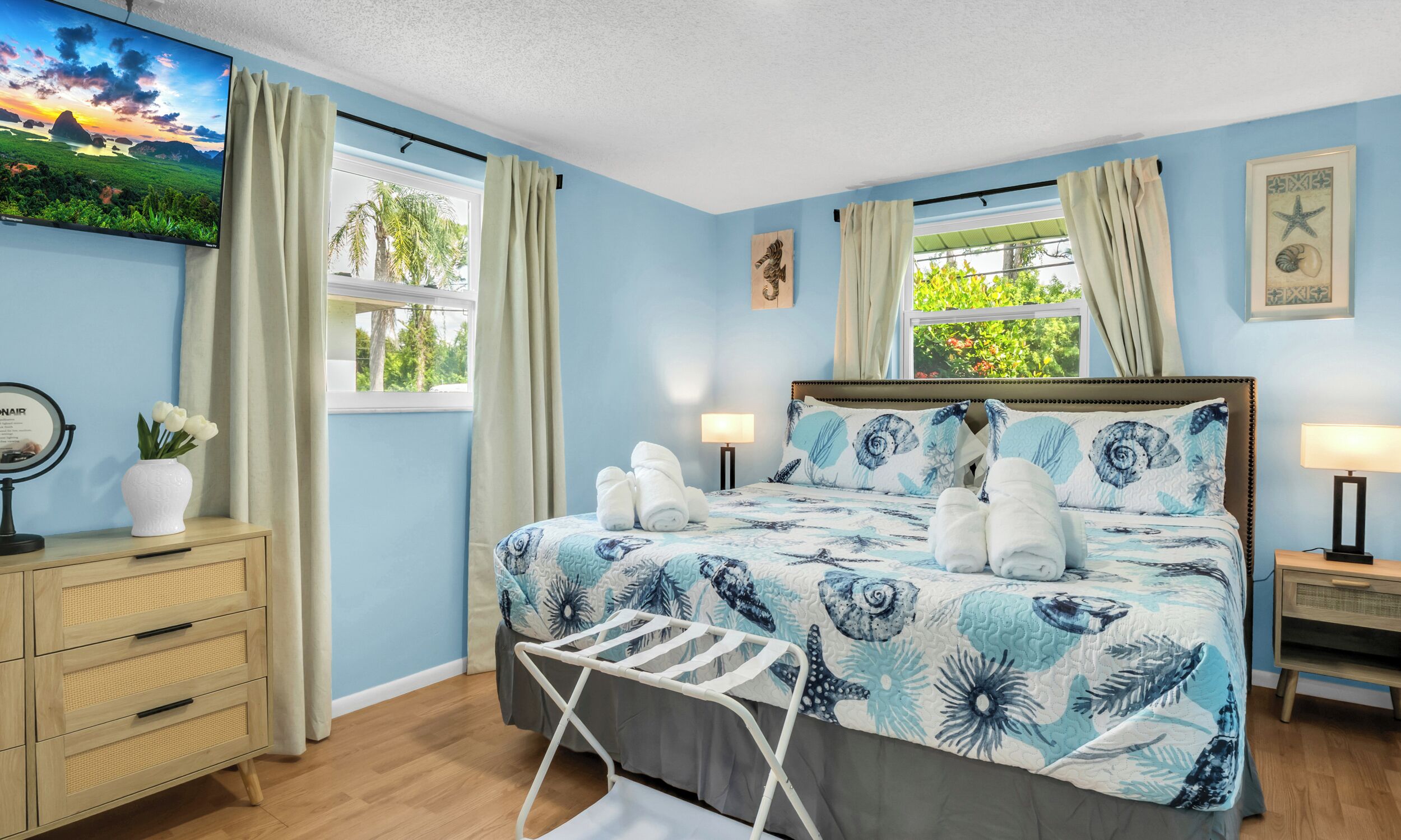 A bedroom with a bed, a nightstand, a dresser, a window with curtains, and a painting on the wall.