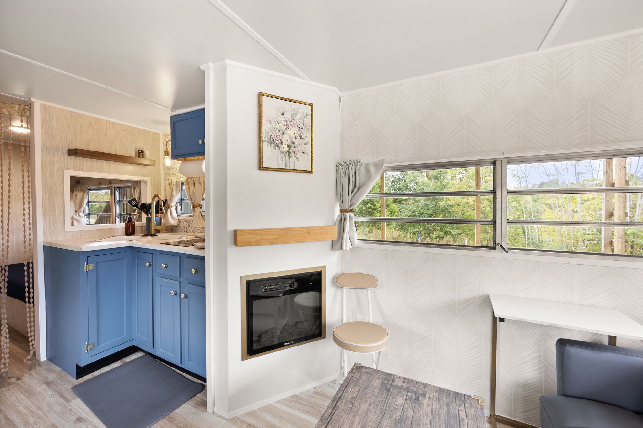 Una cucina moderna con mobili blu, forno integrato e una finestra vista verde.