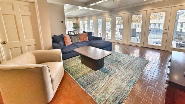 A spacious living room with a sectional sofa, a coffee table, and a large window offering a view of the outdoors.