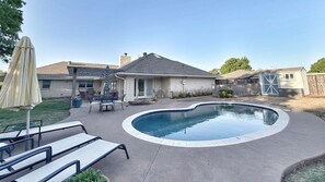 Un jardin avec une piscine, des meubles de patio et un espace patio couvert.