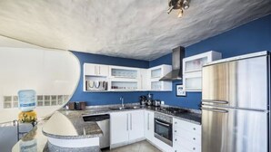 Una cocina moderna con armarios blancos, un refrigerador de acero inoxidable y una isla con encimera de granito.