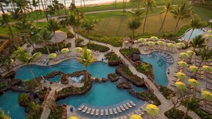 Ein Resort mit mehreren Schwimmbecken, Palmen und Liegebereichen.