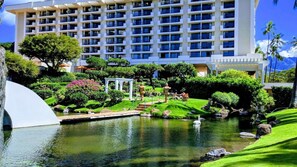 Ein Hotel mit einem großen Gebäude, einem Teich mit einem Schwan und gepflegten Gärten.