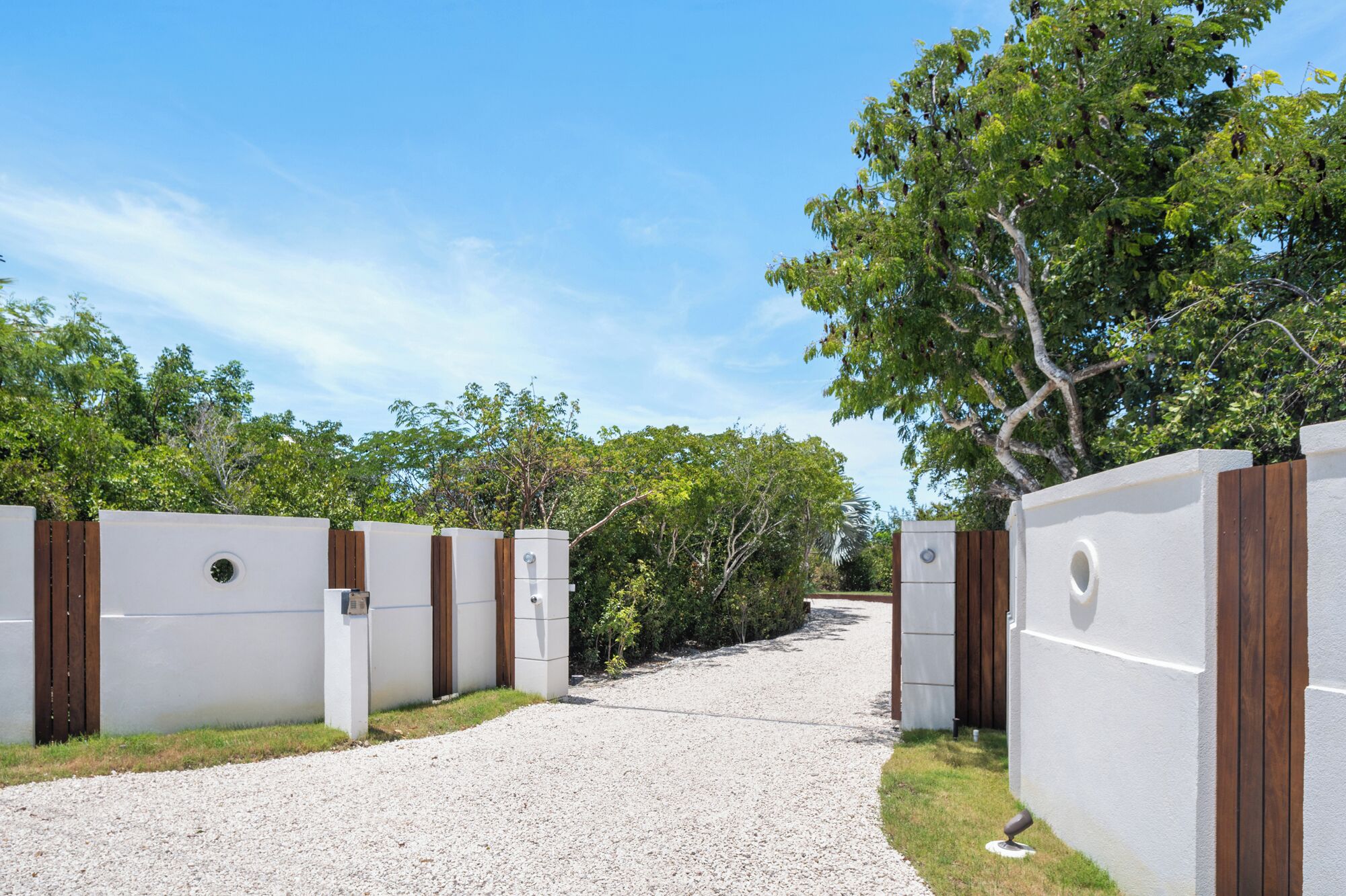 A gravel pathway leading through a gated area with white walls and wooden accents.