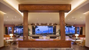 A lobby with a reception desk, seating area, and large windows overlooking a beach. - Ocean View 2BR Middle Floor Villa – Hyatt Kaʻanapali Beach Resort (Lahaina)