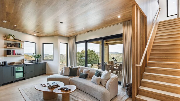 Uma sala de estar moderna com uma escada de madeira, um sofá e uma mesa de centro.