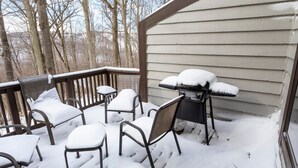Ein überdachter Sitzbereich im Freien mit Metallstühlen und einem Tisch, umgeben von Schnee.