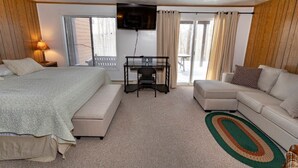Ein Schlafzimmer mit einem Bett, einem Schreibtisch, einer Couch und einem Fernseher.