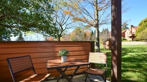 An outdoor seating area with a table and two chairs, a potted plant, and a wooden fence in the background. - Deluxe 1BR w/ Patio | Golf Nearby + Resort Pools (Champion)