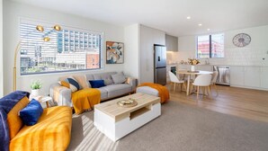 A modern living room with a sofa, coffee table, and a dining area with chairs and a table.