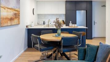 A modern kitchen with white cabinets, a central island, and a dining area with a round table and chairs.