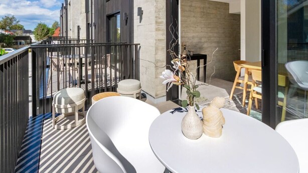 A modern outdoor patio with a round table, white chairs, and a vase with flowers. - Executive Accommodation. 3 Bed, 3 bath + Garage (Christchurch)
