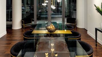 Een moderne eetruimte met een tafel met glazen blad, zwarte beklede stoelen en een gouden decoratief object in het midden.