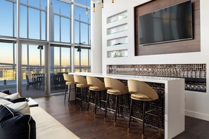 Eine moderne Bar mit großem Fernseher, Weingläsern und Blick auf die Stadt.