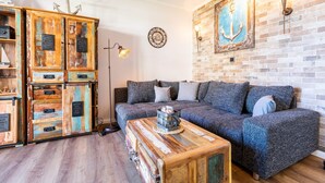Un salon chaleureux avec un meuble en bois d’époque, un canapé moderne et un mur en briques.