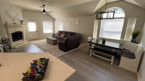Un salon spacieux avec une cheminée, un canapé, une table à manger et un ventilateur de plafond.