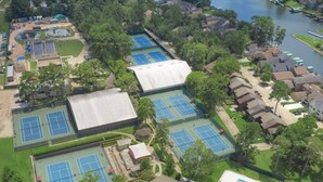 Vue aérienne d’un complexe comprenant plusieurs courts de tennis, une piscine et des immeubles résidentiels.