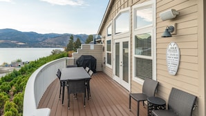 A deck with outdoor furniture, a barbecue grill, and a sign about lake rules.
