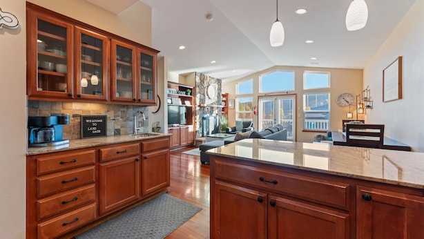 A spacious kitchen with wooden cabinets, a large island, and a stone backsplash.