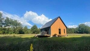 Une cabane en bois avec un toit en pente, une véranda et une petite terrasse.