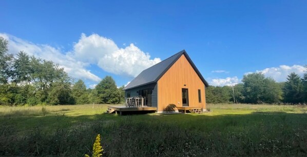 A wooden cabin with a sloped roof, a porch, and a small deck.