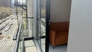 Un appartement moderne doté de grandes fenêtres donnant sur une rue animée et d’autres immeubles.