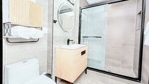 Une salle de bain moderne avec une douche à parois de verre, un meuble-lavabo en bois et un porte-serviettes.