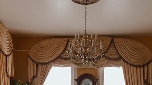A traditional living room with a chandelier, two sofas, a coffee table, and a large wooden clock. - The Lasker Inn - B&B (Galveston)