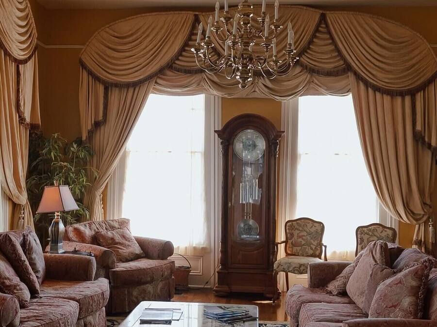 A traditional living room with a chandelier, two sofas, a coffee table, and a large wooden clock.