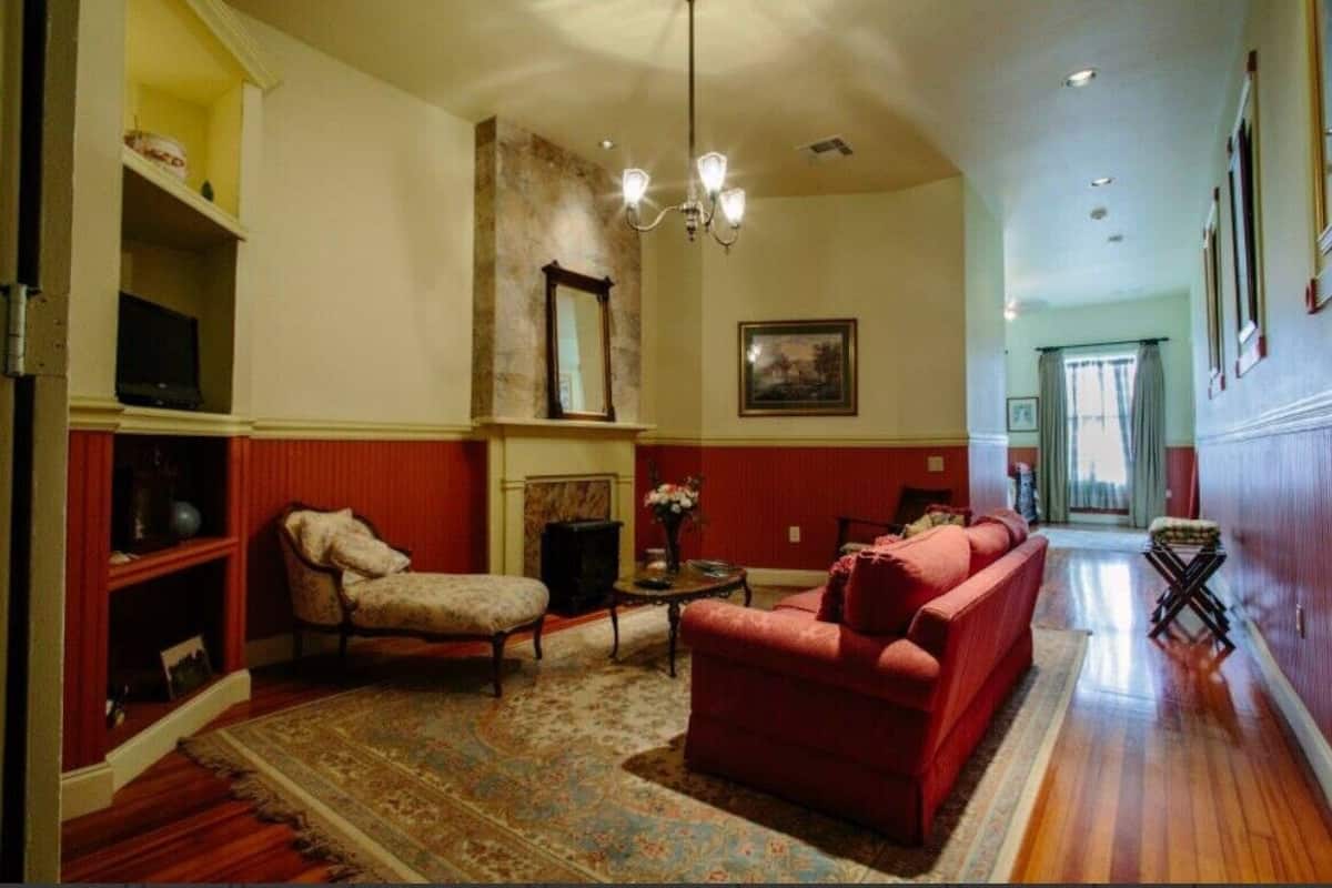 A living room with a red sofa, a patterned rug, a wooden coffee table, and a chandelier.