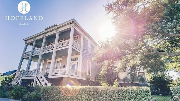 A two-story building with a balcony, a staircase, and a well-maintained hedge in front. - The Lasker Inn - B&B (Galveston)