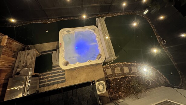A hot tub with a blue light, surrounded by a wooden deck and a stone wall. - LUXURY GOLF GETAWAY DOWNTOWN BOISE (Boise)